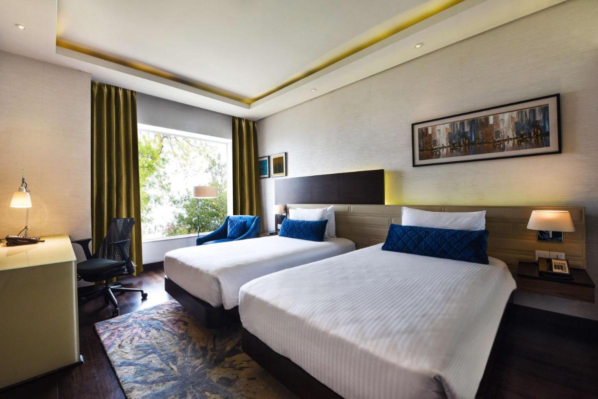 a hotel room with two beds and a window at DoubleTree by Hilton Gurugram Baani Square in Gurgaon