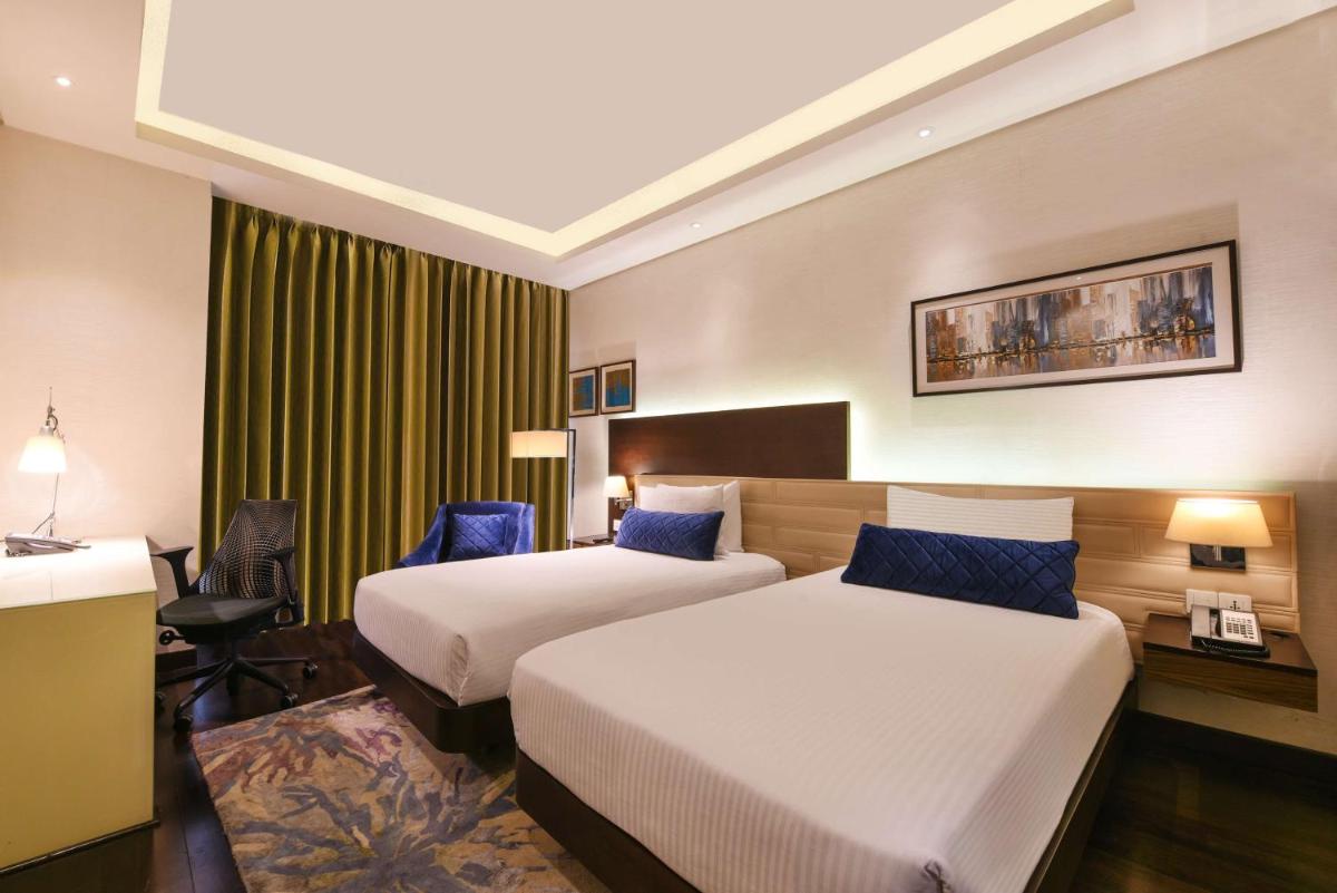 a hotel room with two beds and a desk at DoubleTree by Hilton Gurugram Baani Square in Gurgaon