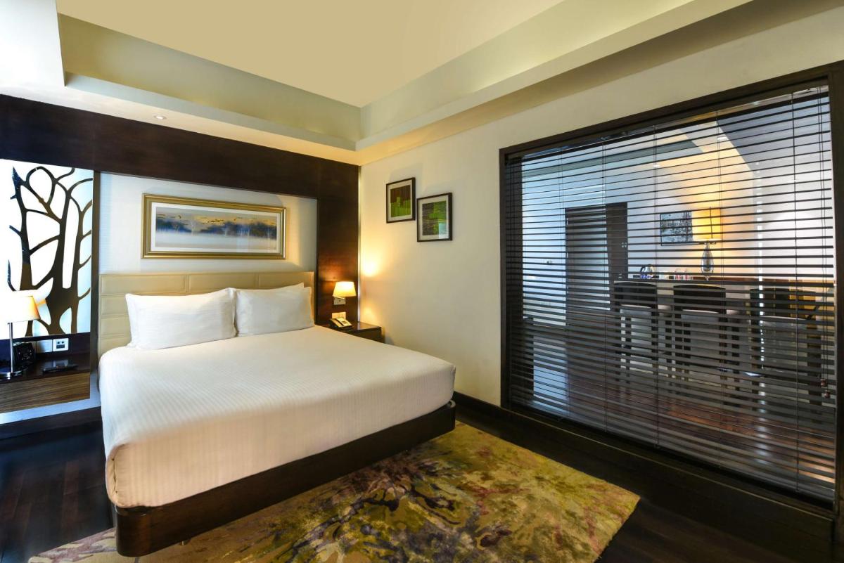 a bedroom with a bed and a large window at DoubleTree by Hilton Gurugram Baani Square in Gurgaon