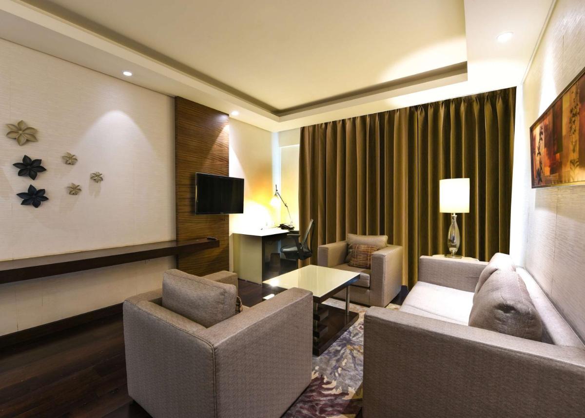a hotel room with two chairs and a couch and a table at DoubleTree by Hilton Gurugram Baani Square in Gurgaon