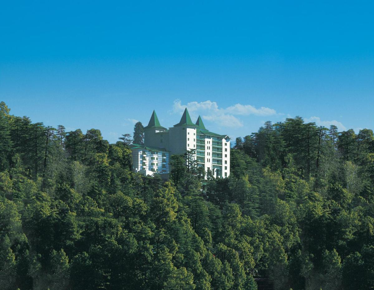 a building on the top of a hill with trees at The Oberoi Cecil in Shimla