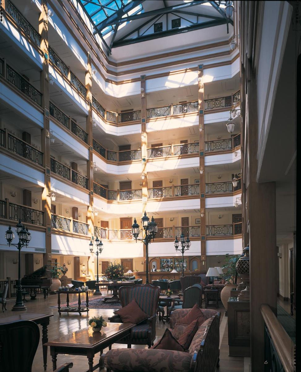 a large lobby with tables and chairs in a building at The Oberoi Cecil in Shimla
