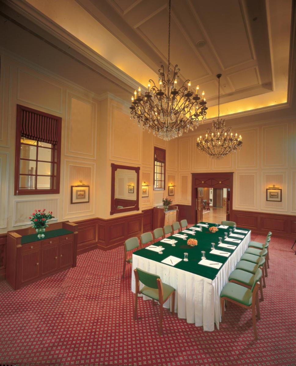 a conference room with a long table and green chairs at The Oberoi Cecil in Shimla