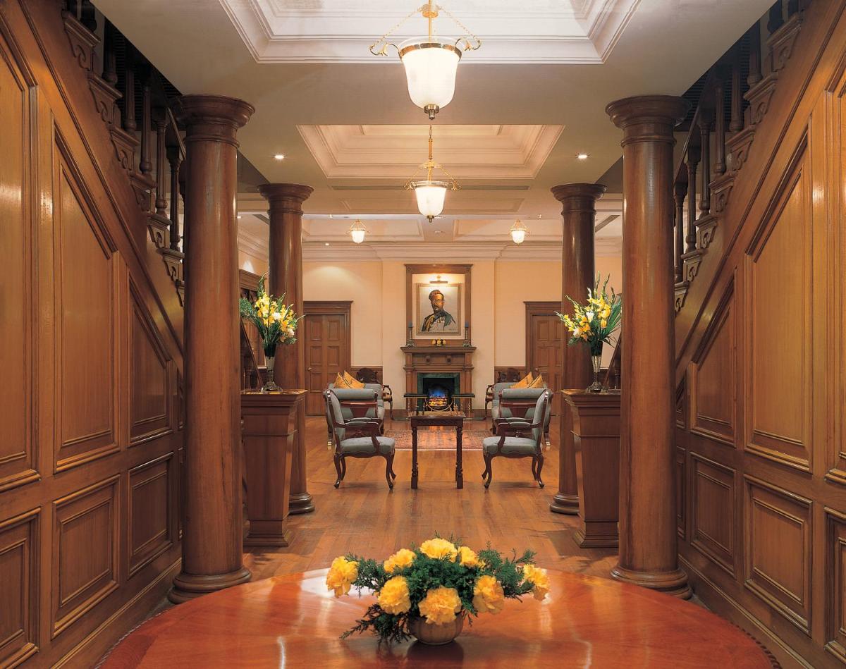 a hallway with columns and a table with flowers on it at The Oberoi Cecil in Shimla