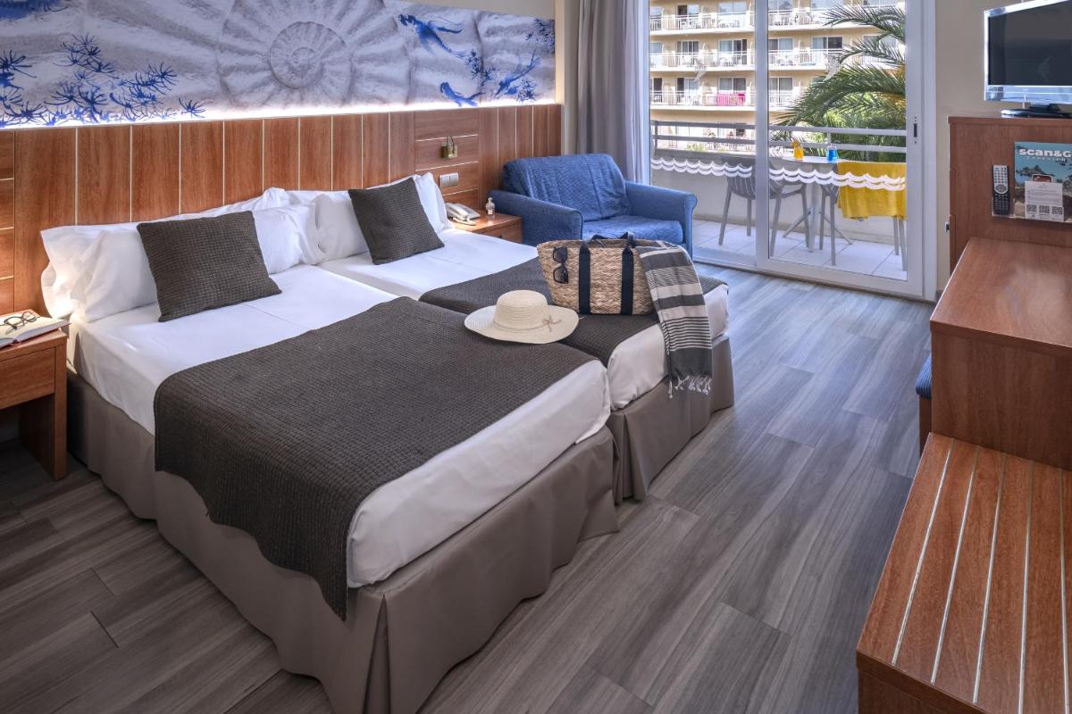 Una habitación de hotel con una cama grande y un televisor. en GHT Aquarium & Spa, en Lloret de Mar