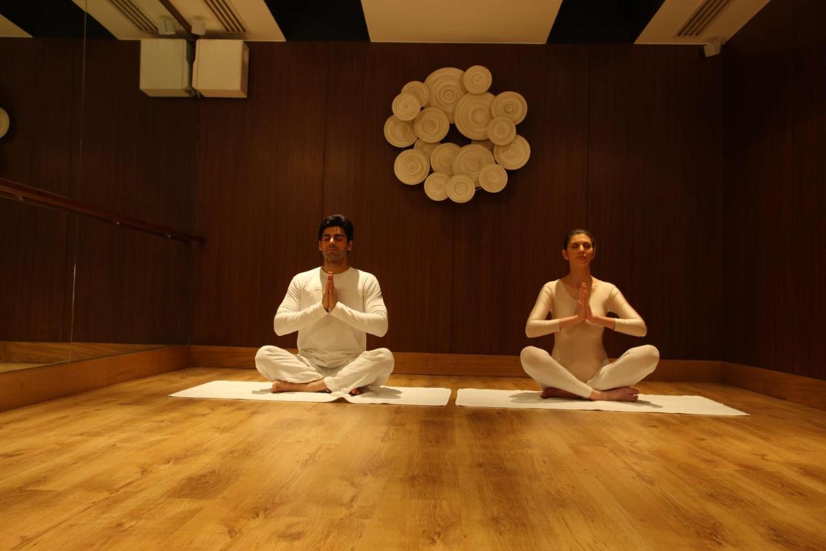 two people sitting in a room doing yoga at Radisson Blu Plaza Delhi Airport in New Delhi two people sitting in a room doing yoga at Radisson Blu Plaza Delhi Airport in New Delhi
