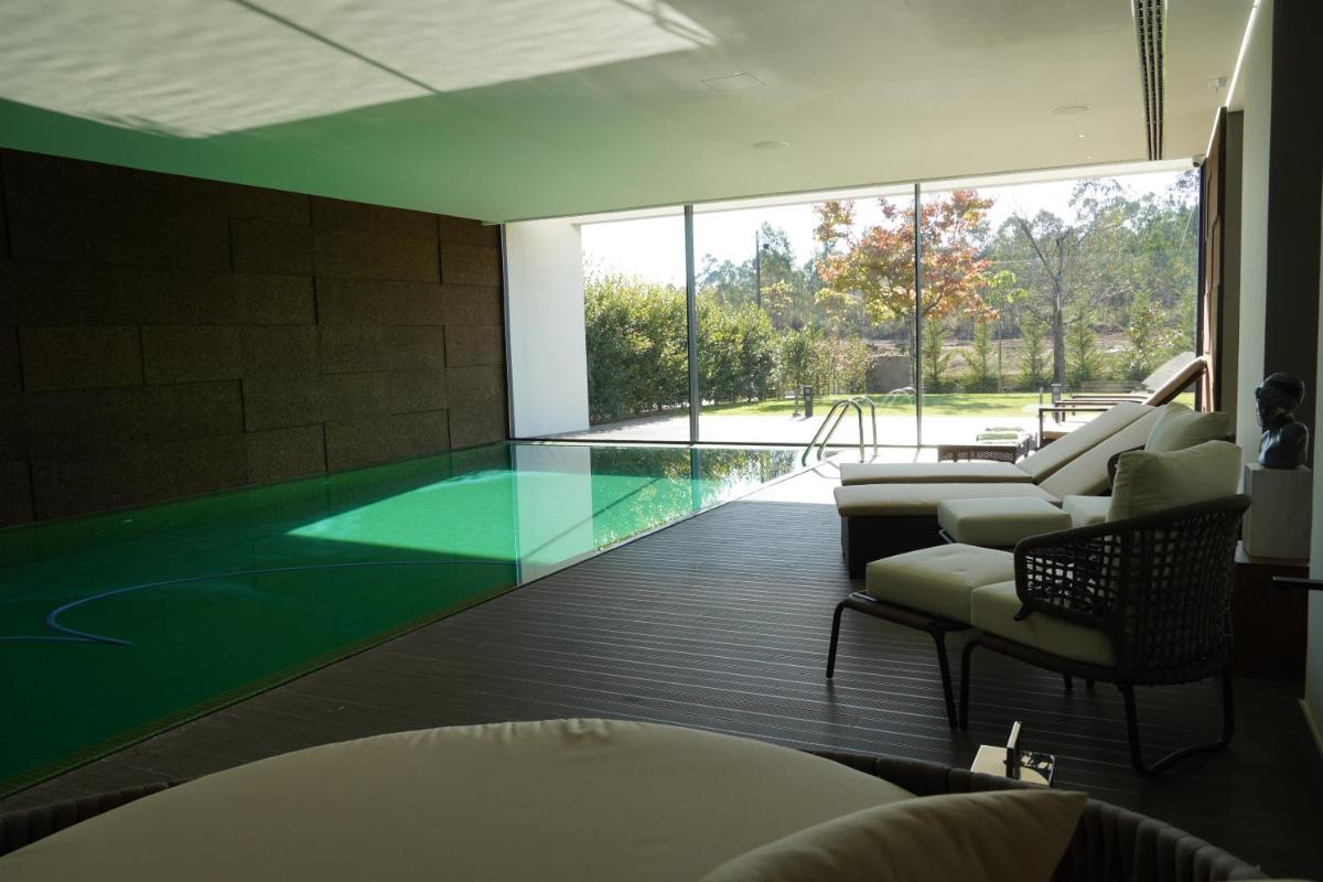 um quarto com uma piscina com um sofá e cadeiras em DS Hotel Lusopark em Santa Maria da Feira