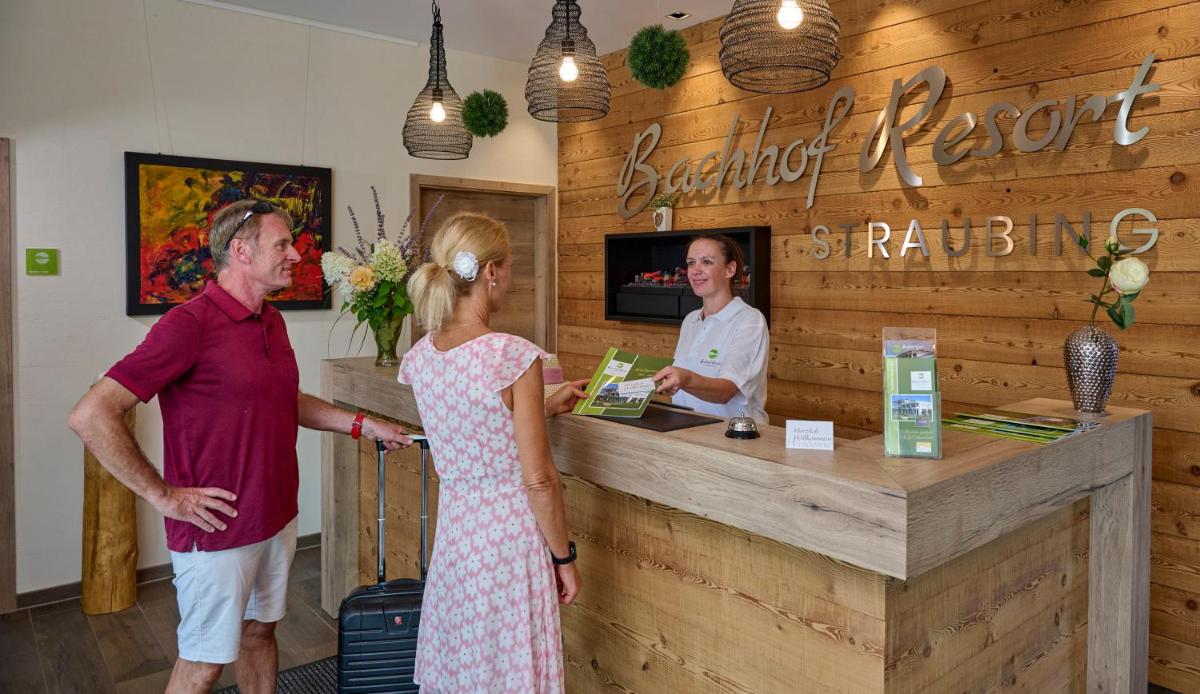 Ein Mann und eine Frau stehen vor einer Kasse in der Unterkunft Bachhof Resort Apartments in Kirchroth