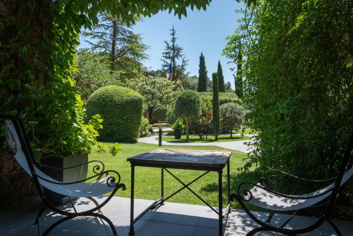 deux chaises et une table dans un jardin dans l'établissement Hostellerie Les Gorges De Pennafort, à Callas