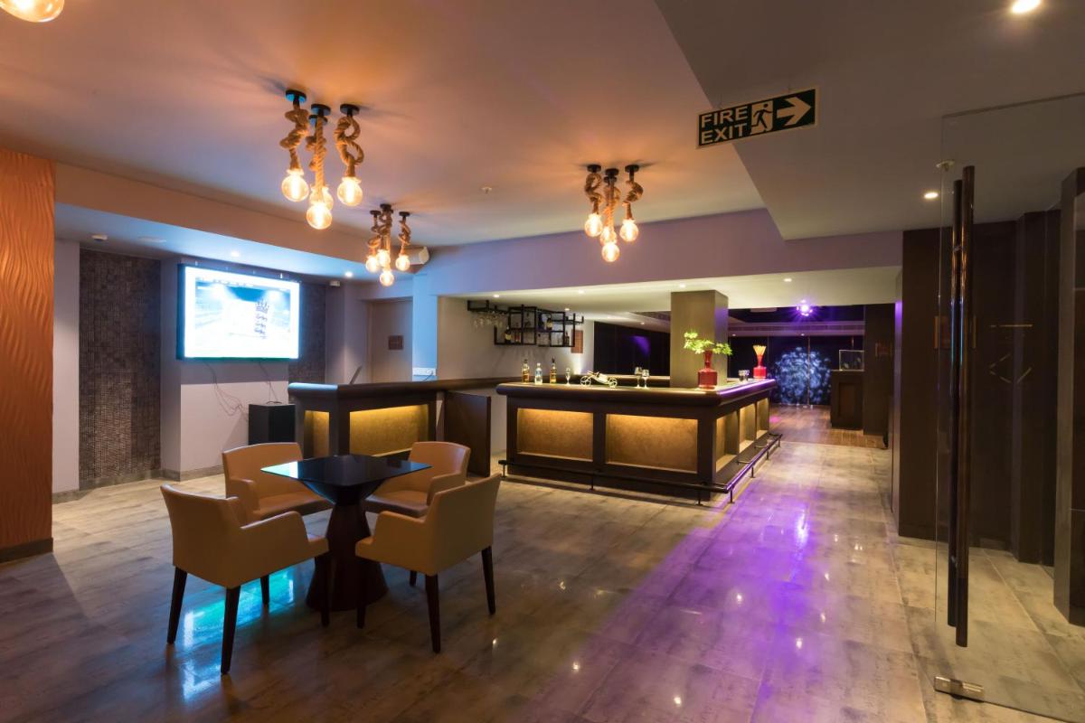 a lobby with a bar with chairs and a table at Ramada Plaza by Wyndham Lucknow in Lucknow