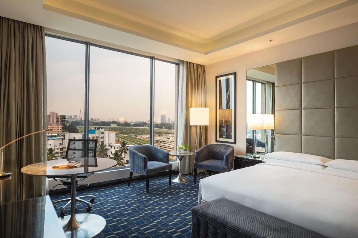 a hotel room with a bed and a desk and a window at Renaissance Bengaluru Race Course Hotel in Bengaluru