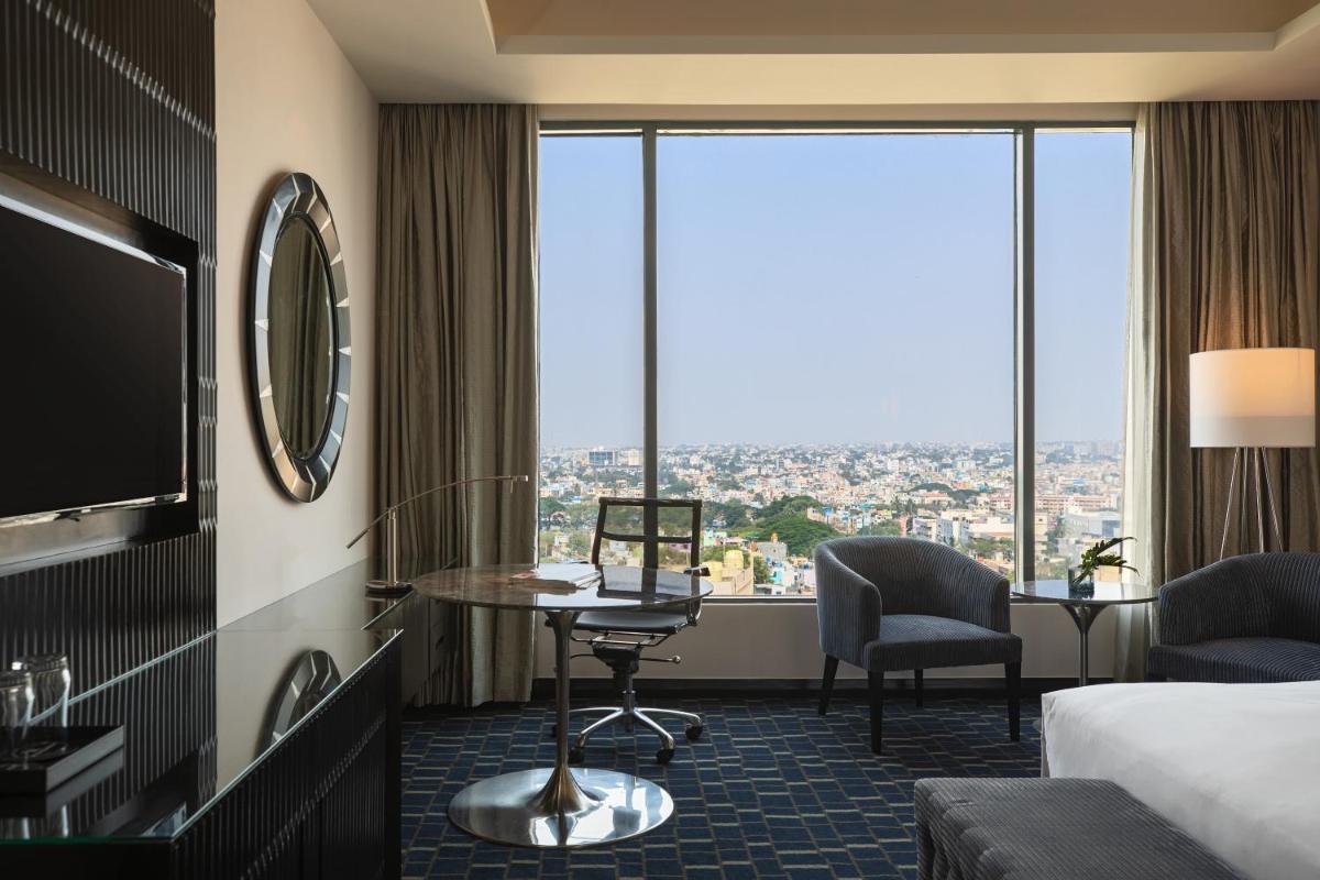 a hotel room with a bed and a desk and a tv at Renaissance Bengaluru Race Course Hotel in Bengaluru