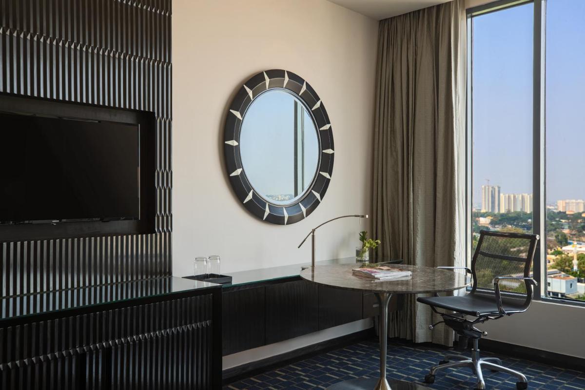 a hotel room with a table and a mirror at Renaissance Bengaluru Race Course Hotel in Bengaluru
