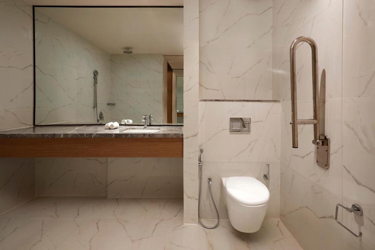 a bathroom with a toilet and a sink and a mirror at Sheraton Hyderabad Hotel in Hyderabad