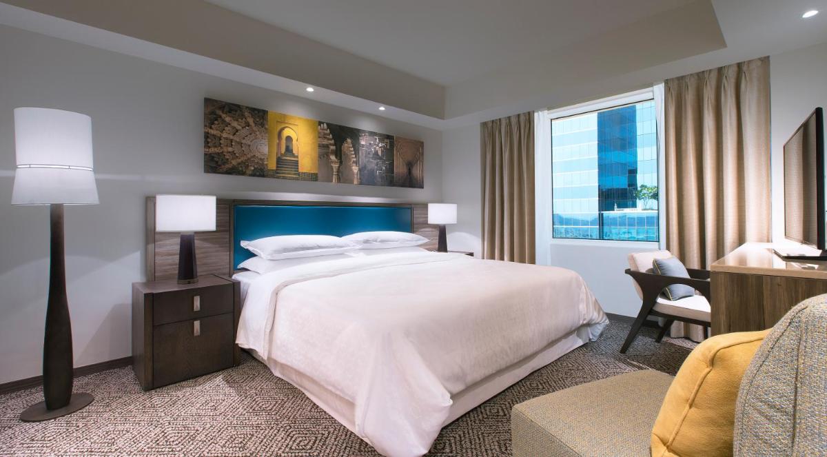 a bedroom with a large white bed and a window at Sheraton Hyderabad Hotel in Hyderabad