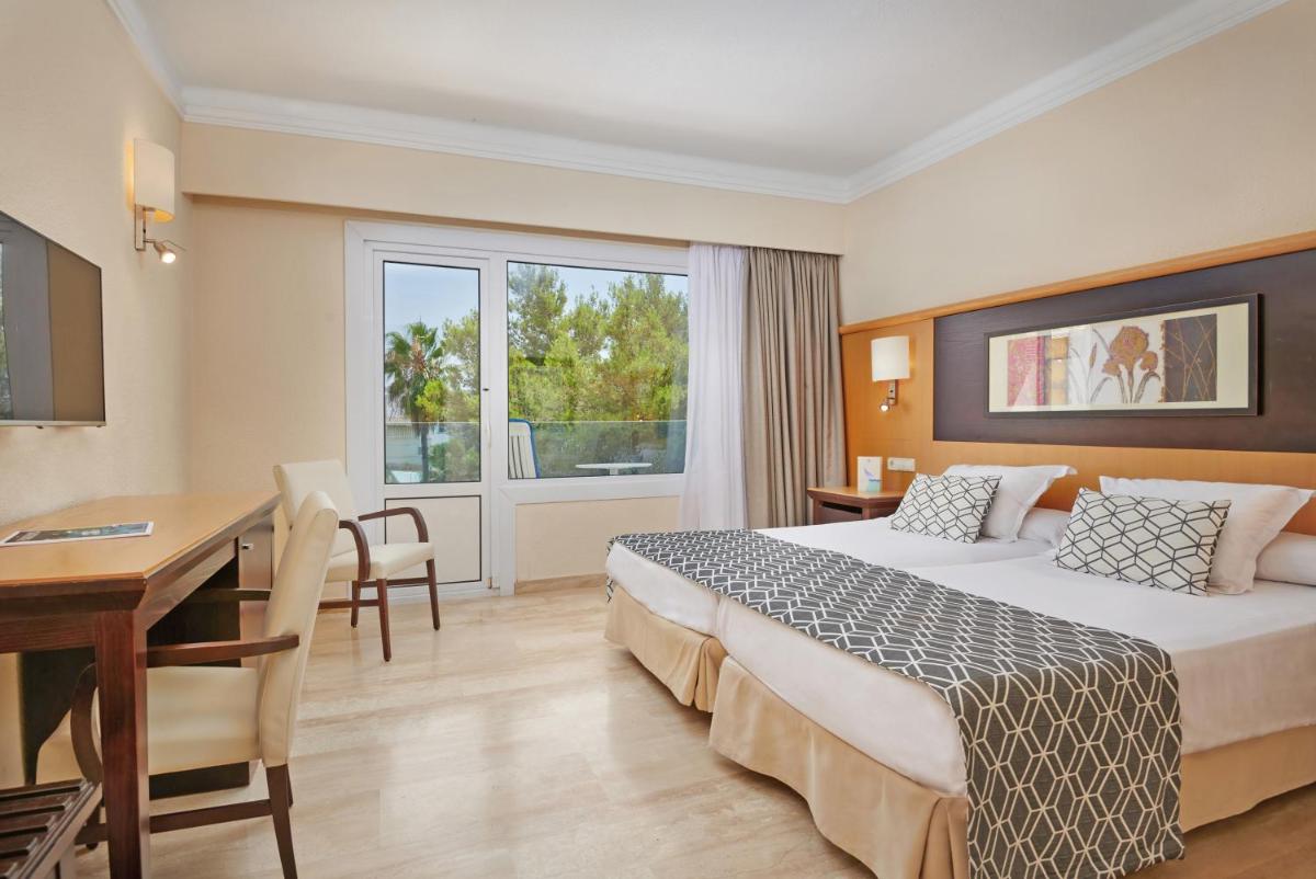 Una habitación de hotel con una cama, una mesa y un escritorio. en Grupotel Nilo & Spa, en Paguera