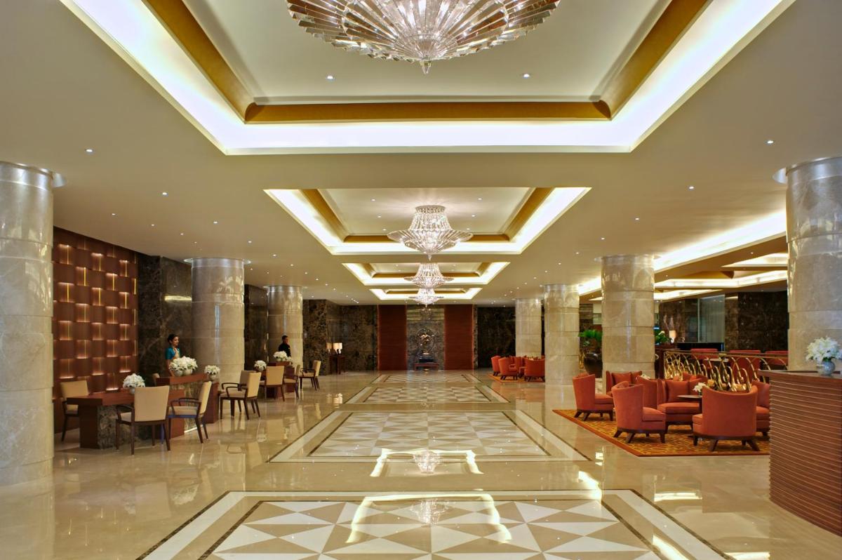 a hotel lobby with a chandelier and tables and chairs at Taj Coromandel in Chennai +53 photos