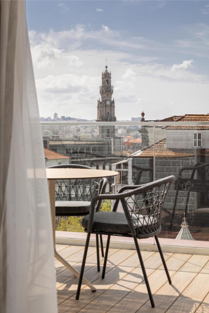 uma cadeira numa varanda com vista para um edifício em Wine & Books Porto Hotel - Small Luxury Hotels Of The World no Porto