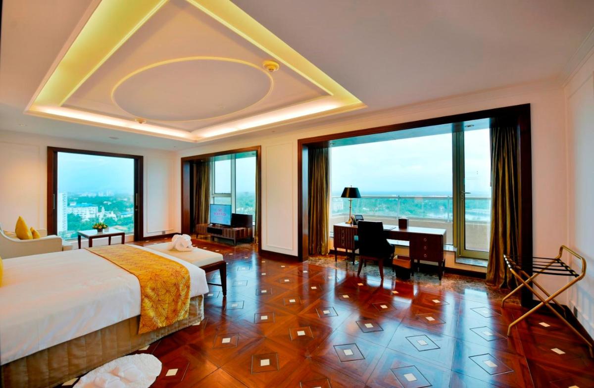 a bedroom with a bed and a desk and windows at Crowne Plaza Kochi by IHG in Cochin