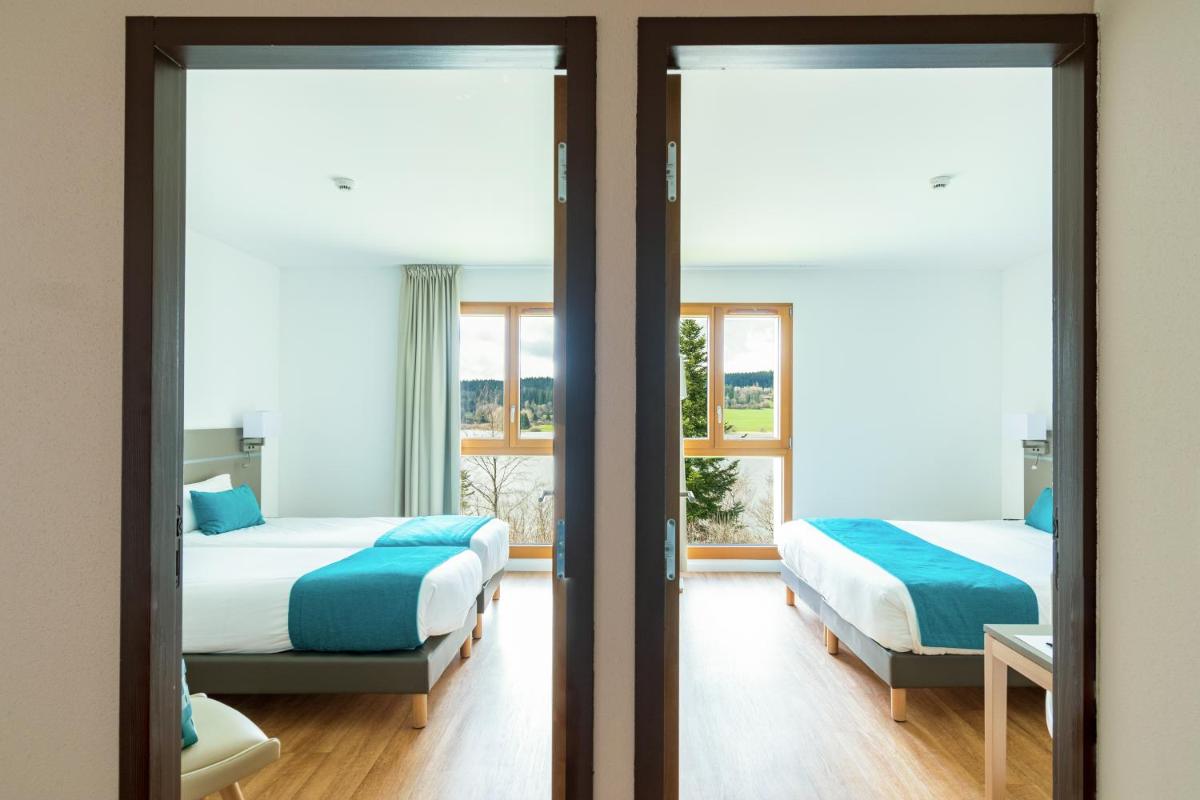 deux lits dans une chambre avec deux fenêtres dans l'établissement Hotel Spa Les Rives Sauvages, à Malbuisson