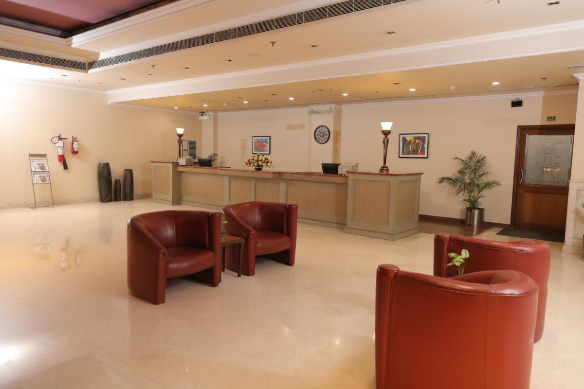 a waiting room with leather chairs and a reception desk at The Piccadily in Lucknow