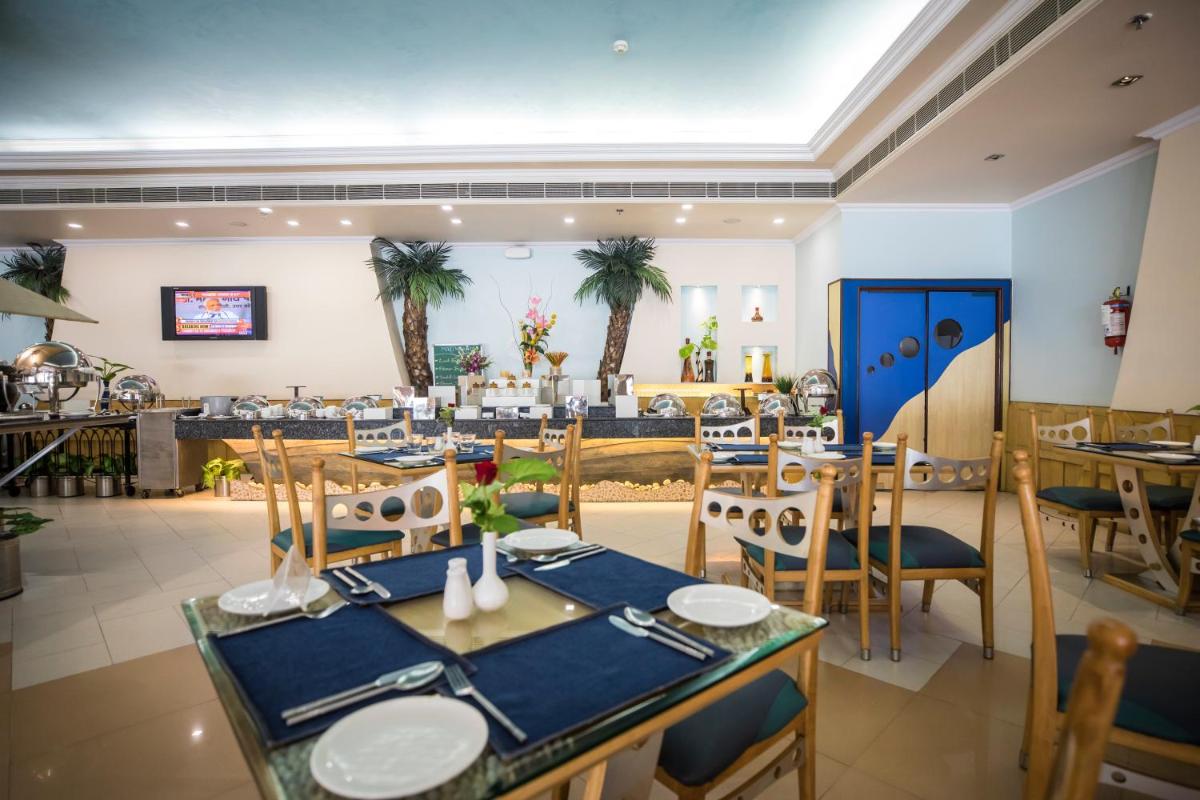 a restaurant with blue tables and chairs and palm trees at The Piccadily in Lucknow