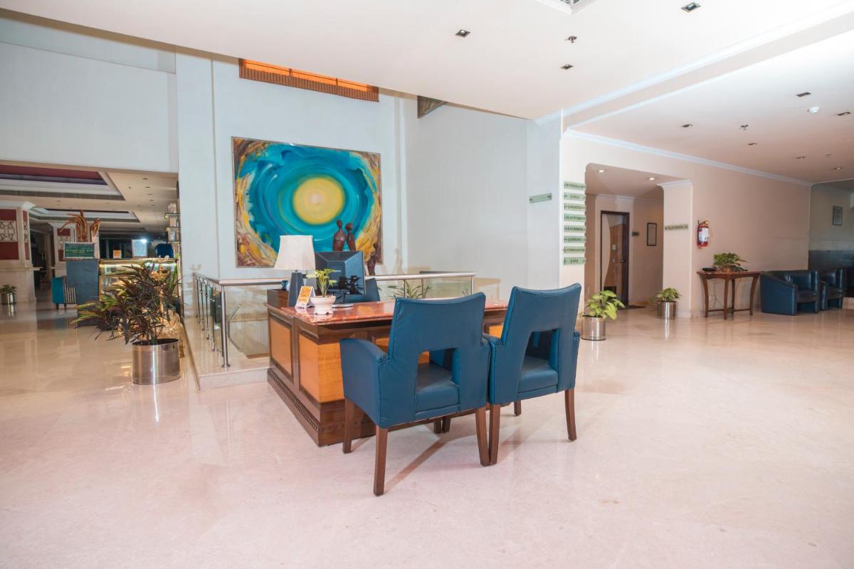 a lobby with a table and blue chairs at The Piccadily in Lucknow