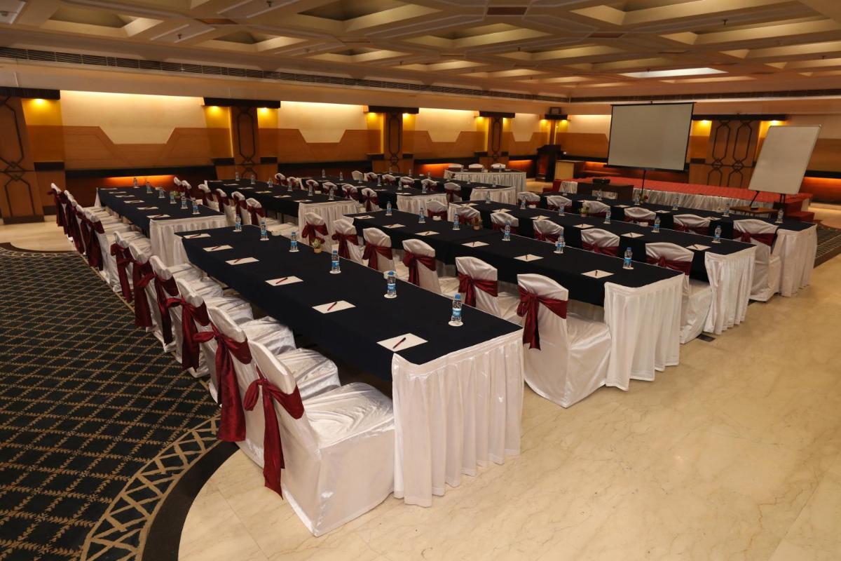 a row of tables in a room with white and red tables at The Piccadily in Lucknow