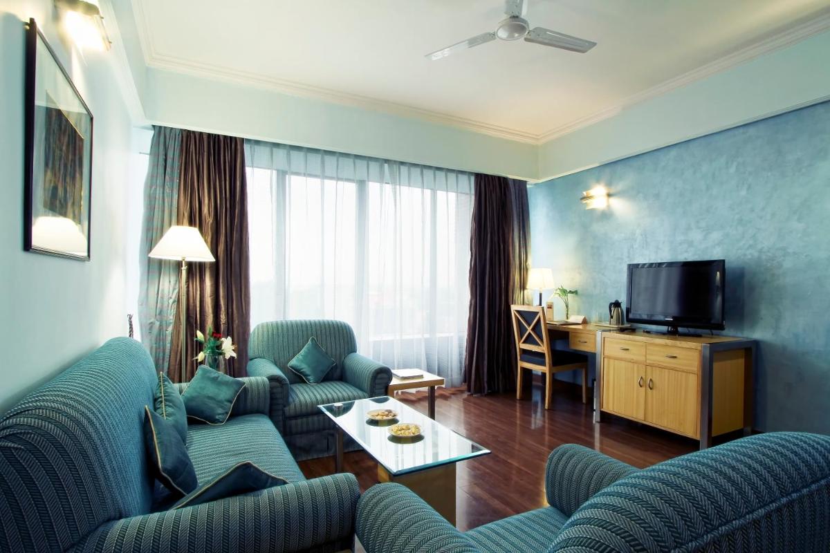 a living room with blue chairs and a television at The Piccadily in Lucknow