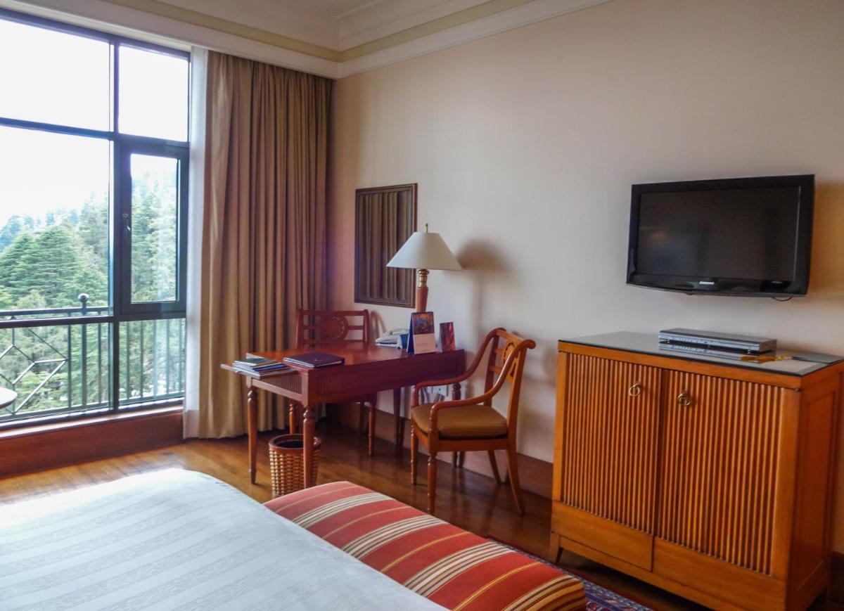 a hotel room with a bed and a desk and a television at Wildflower Hall, An Oberoi Resort, Shimla in Shimla