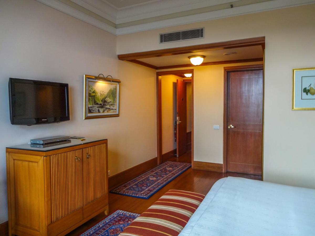 a bedroom with a bed and a flat screen tv at Wildflower Hall, An Oberoi Resort, Shimla in Shimla