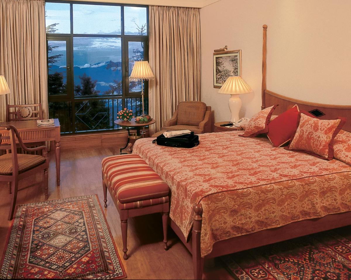 a hotel room with a bed and a large window at Wildflower Hall, An Oberoi Resort, Shimla in Shimla