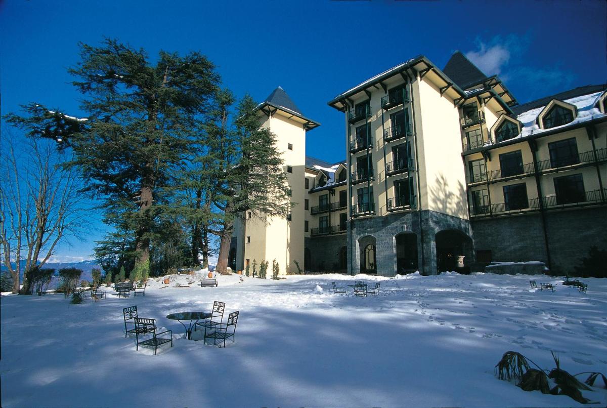 a large building with chairs in the snow at Wildflower Hall, An Oberoi Resort, Shimla in Shimla