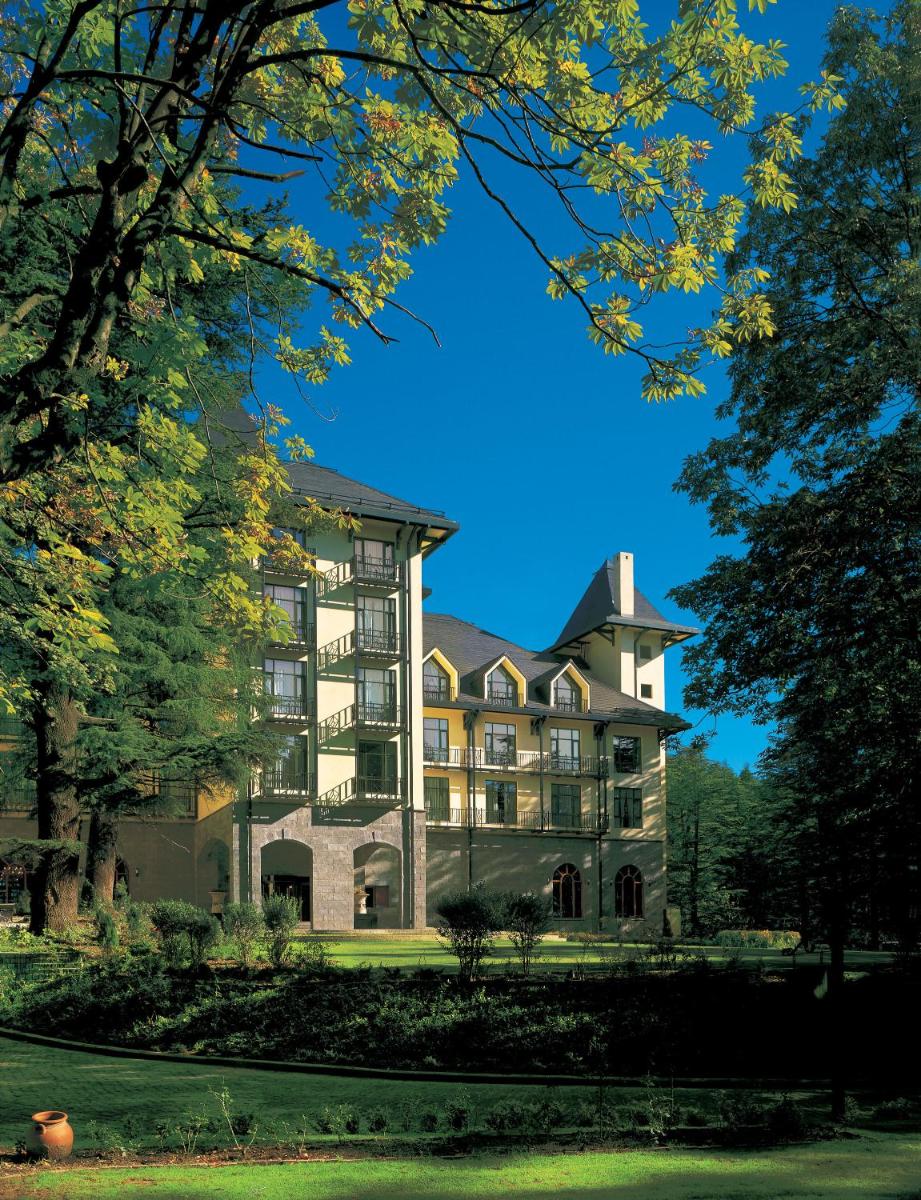 a large building with trees in front of it at Wildflower Hall, An Oberoi Resort, Shimla in Shimla
