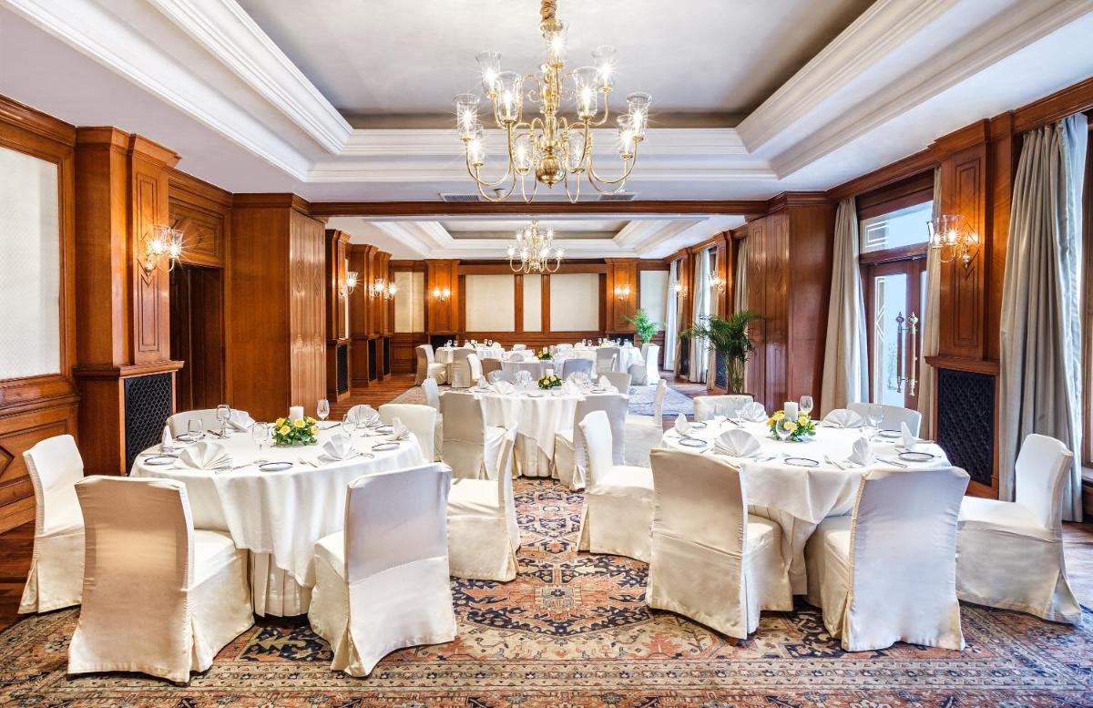 a banquet room with white tables and chairs and a chandelier at Wildflower Hall, An Oberoi Resort, Shimla in Shimla