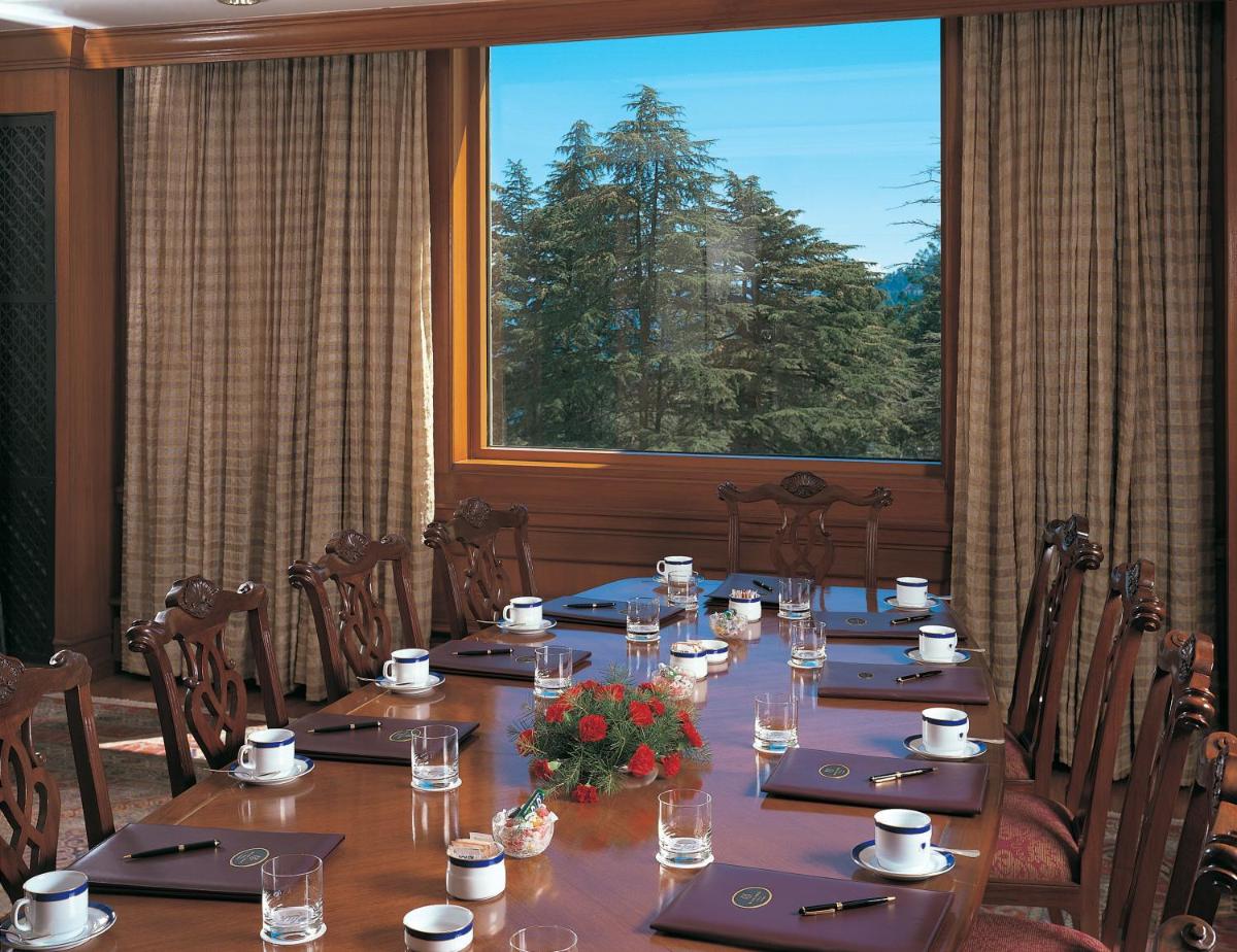 a long table in a room with a large window at Wildflower Hall, An Oberoi Resort, Shimla in Shimla