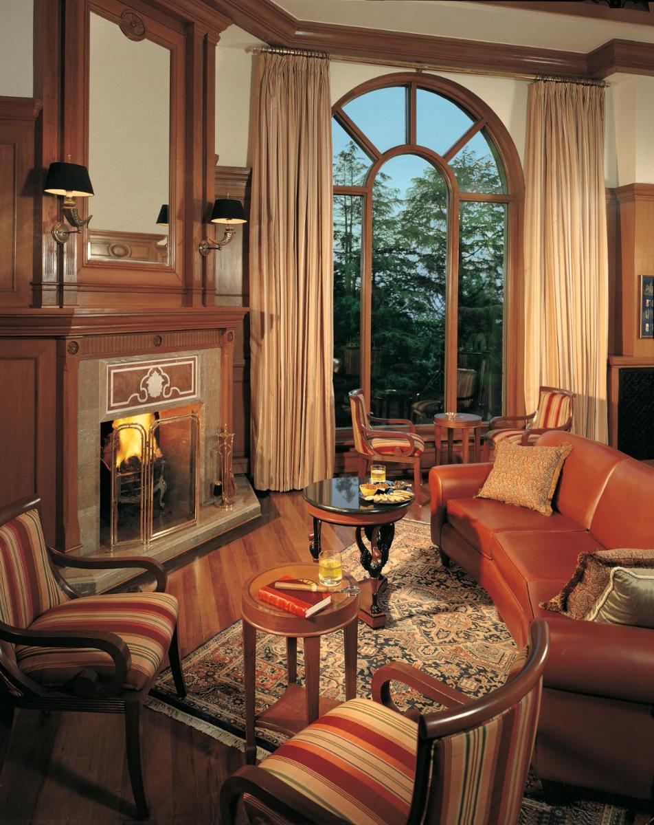 a living room with a couch and a fireplace at Wildflower Hall, An Oberoi Resort, Shimla in Shimla