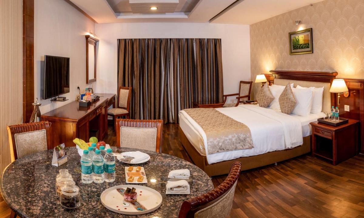 a hotel room with a bed and a table and chairs at Fortune JP Palace, Mysore - Member ITC Hotels' Group in Mysore