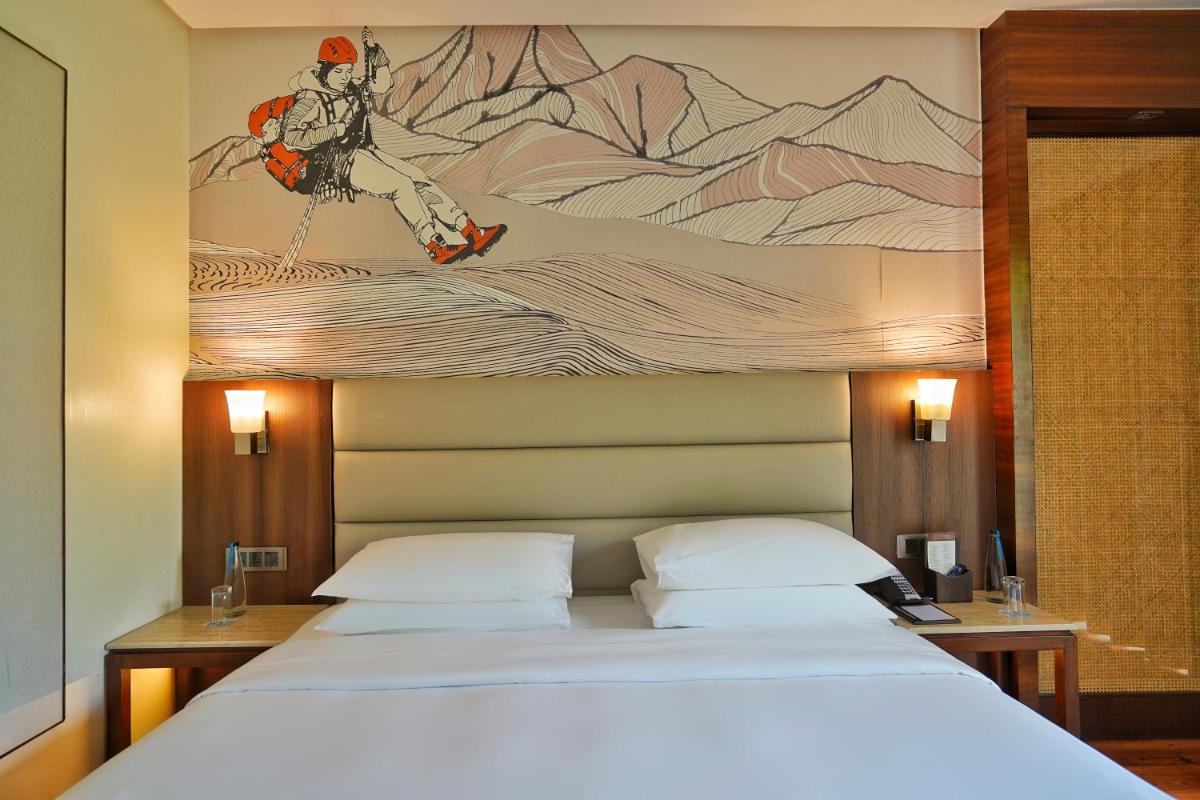 a bedroom with a bed with a painting on the wall at Hyatt Centric Rajpur Road Dehradun in Dehradun