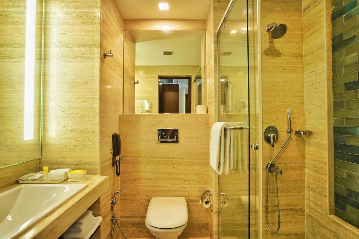 a bathroom with a shower and a toilet and a sink at Hyatt Centric Rajpur Road Dehradun in Dehradun