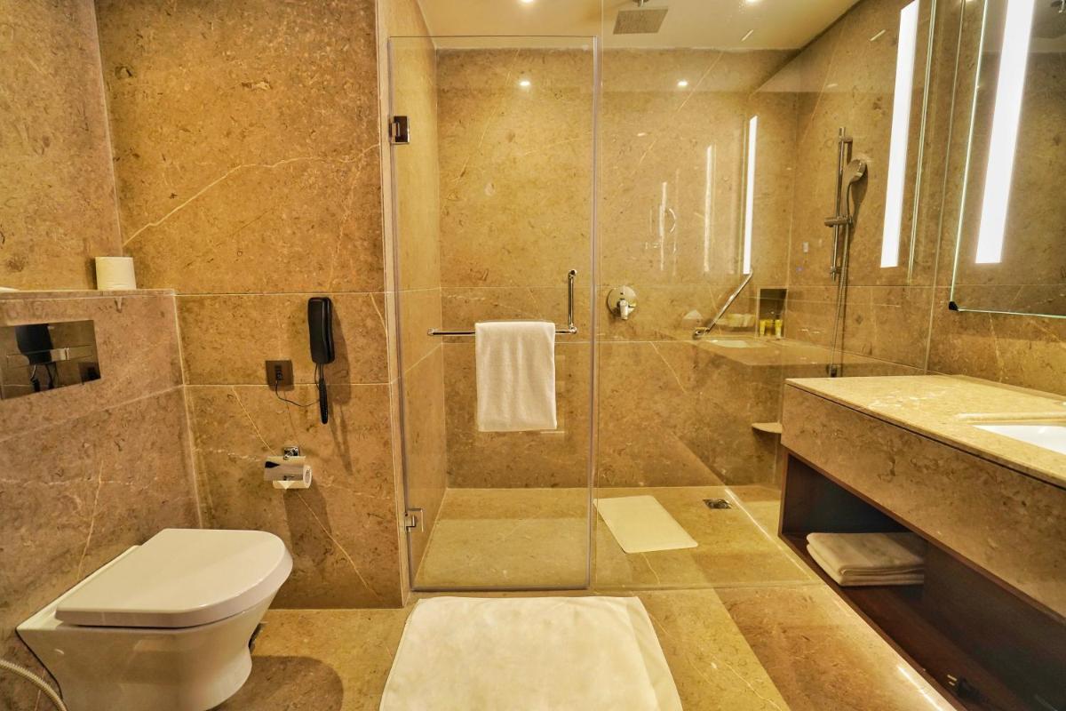 a bathroom with a shower and a toilet and a sink at Hyatt Centric Rajpur Road Dehradun in Dehradun