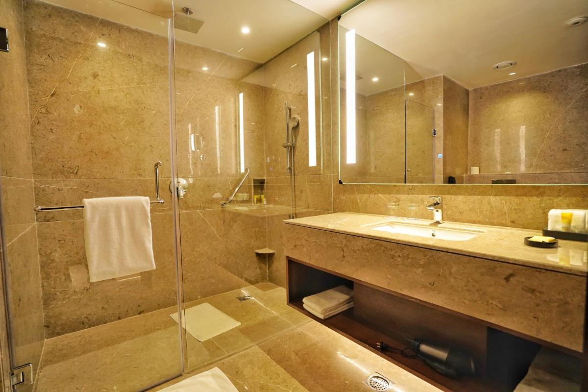 a bathroom with a sink and a glass shower at Hyatt Centric Rajpur Road Dehradun in Dehradun