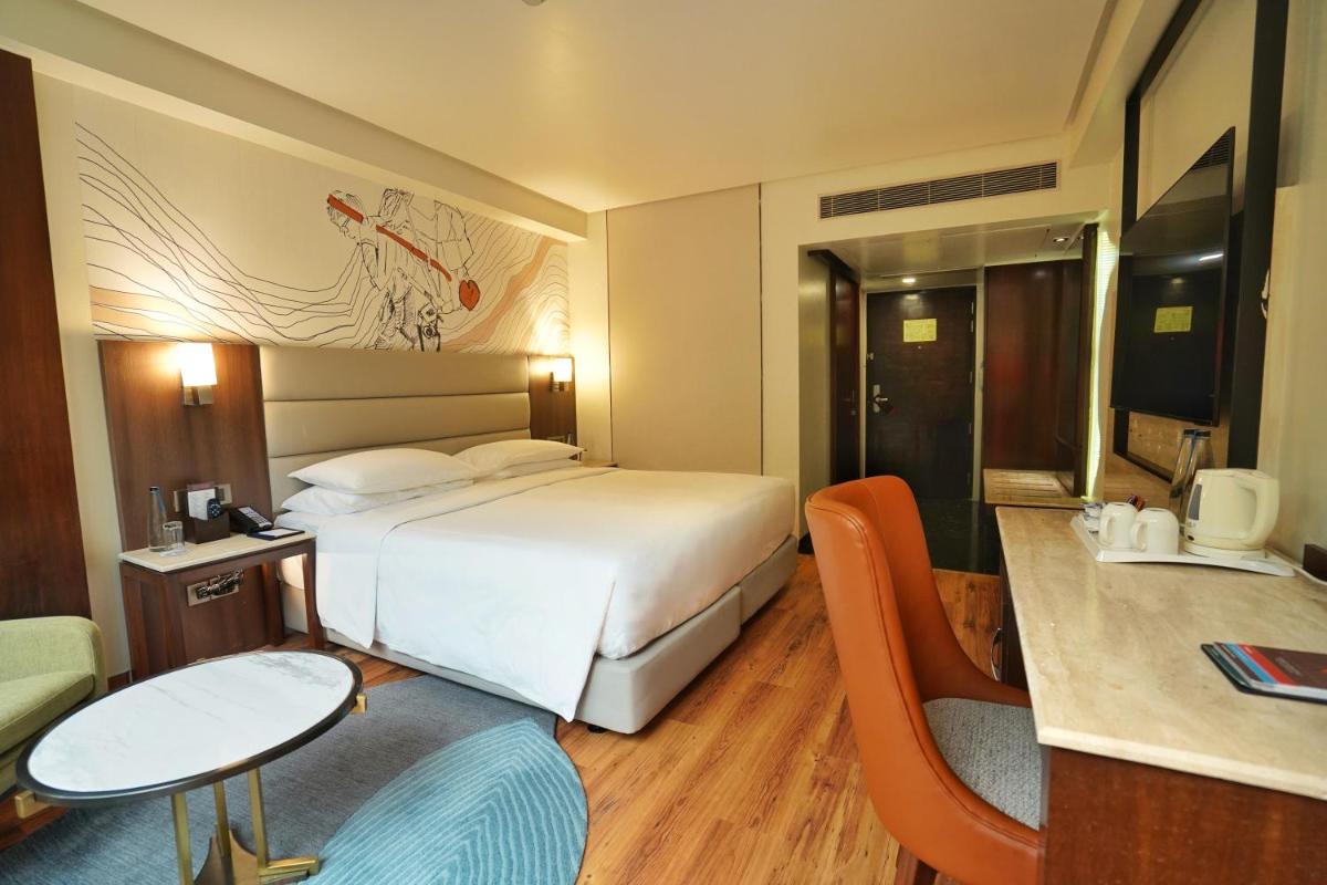 a hotel room with a bed and a table and chairs at Hyatt Centric Rajpur Road Dehradun in Dehradun