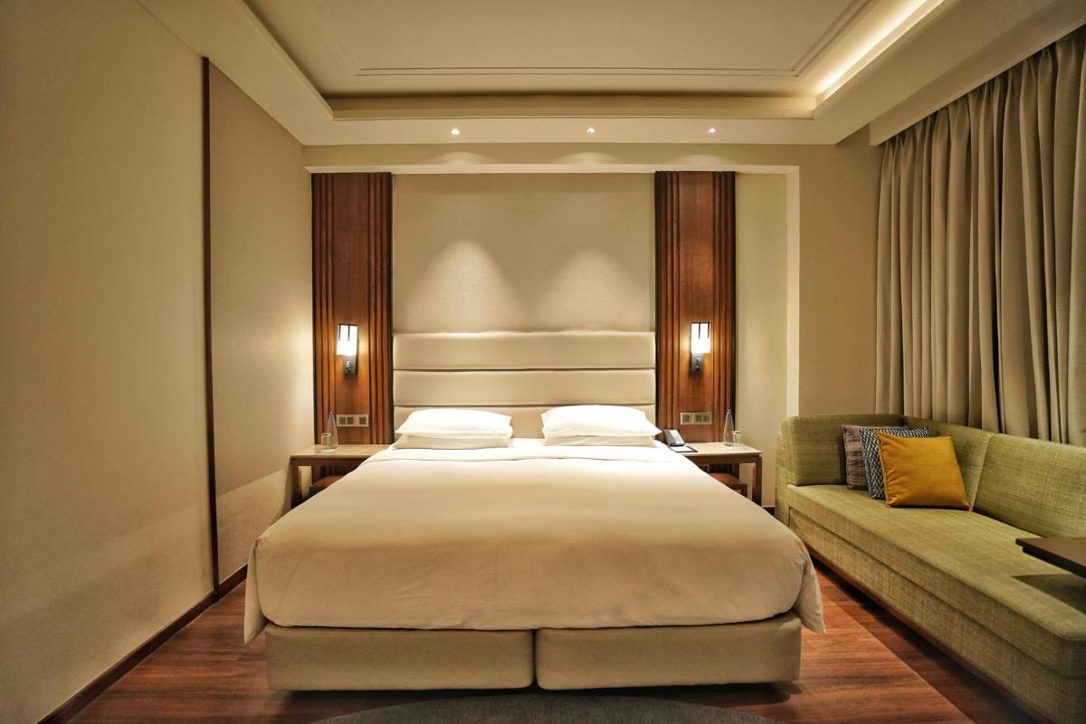 a bedroom with a large bed and a couch at Hyatt Centric Rajpur Road Dehradun in Dehradun