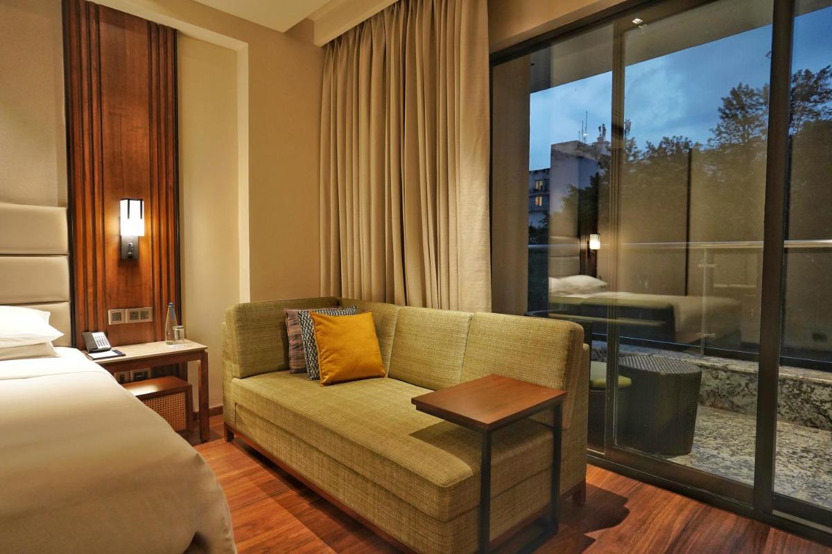 a hotel room with a couch and a bed and a window at Hyatt Centric Rajpur Road Dehradun in Dehradun