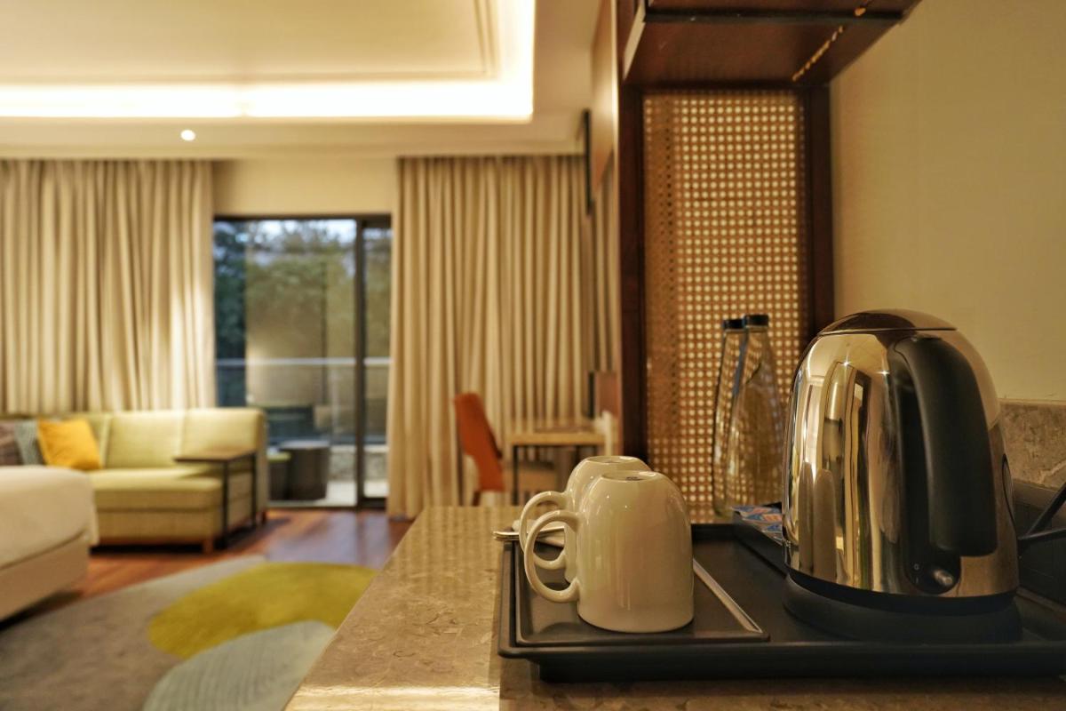 a kitchen counter with a toaster and a living room at Hyatt Centric Rajpur Road Dehradun in Dehradun