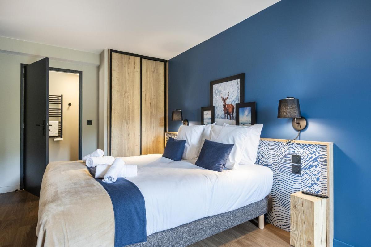 une chambre avec un grand lit aux murs bleus dans l'établissement Résidence Club MMV Le Silvana, à Risoul 63 autres photos