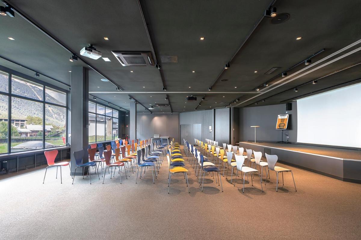 une salle de conférence avec des tables, des chaises et un écran dans l'établissement Alpina Eclectic Hotel, à Chamonix-Mont-Blanc