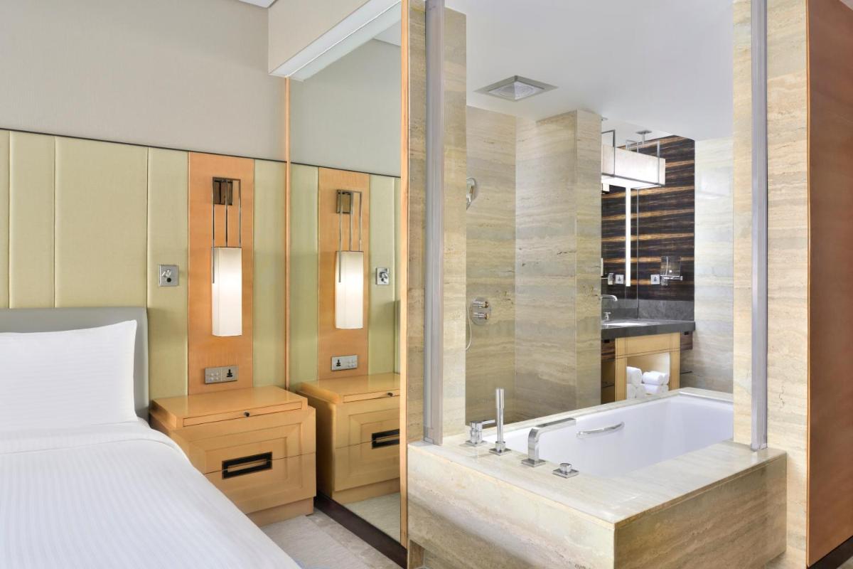 a bathroom with a tub and a bed and a bed and a bed at JW Marriott Hotel New Delhi Aerocity in New Delhi a bathroom with a tub and a bed and a bed and a bed at JW Marriott Hotel New Delhi Aerocity in New Delhi