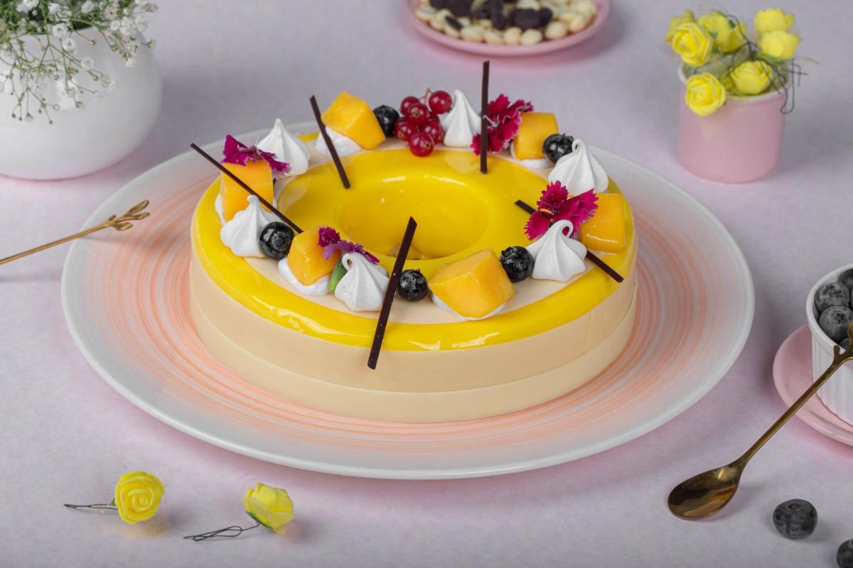 a yellow cake with fruit on top of a table at JW Marriott Hotel New Delhi Aerocity in New Delhi a yellow cake with fruit on top of a table at JW Marriott Hotel New Delhi Aerocity in New Delhi